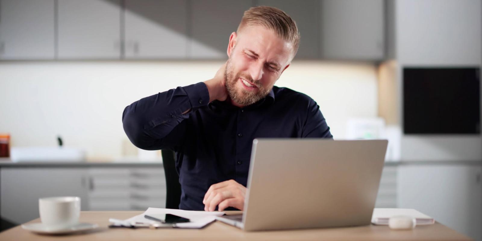 Mann bak laptop på skrivebord