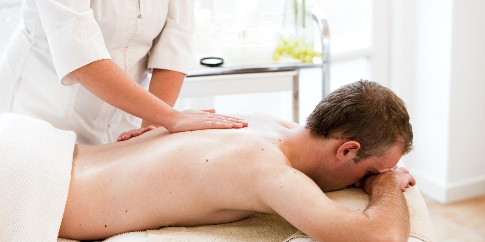 Bilde av hvit mann som ligger på behandlingsbenk og får massasje på ryggen