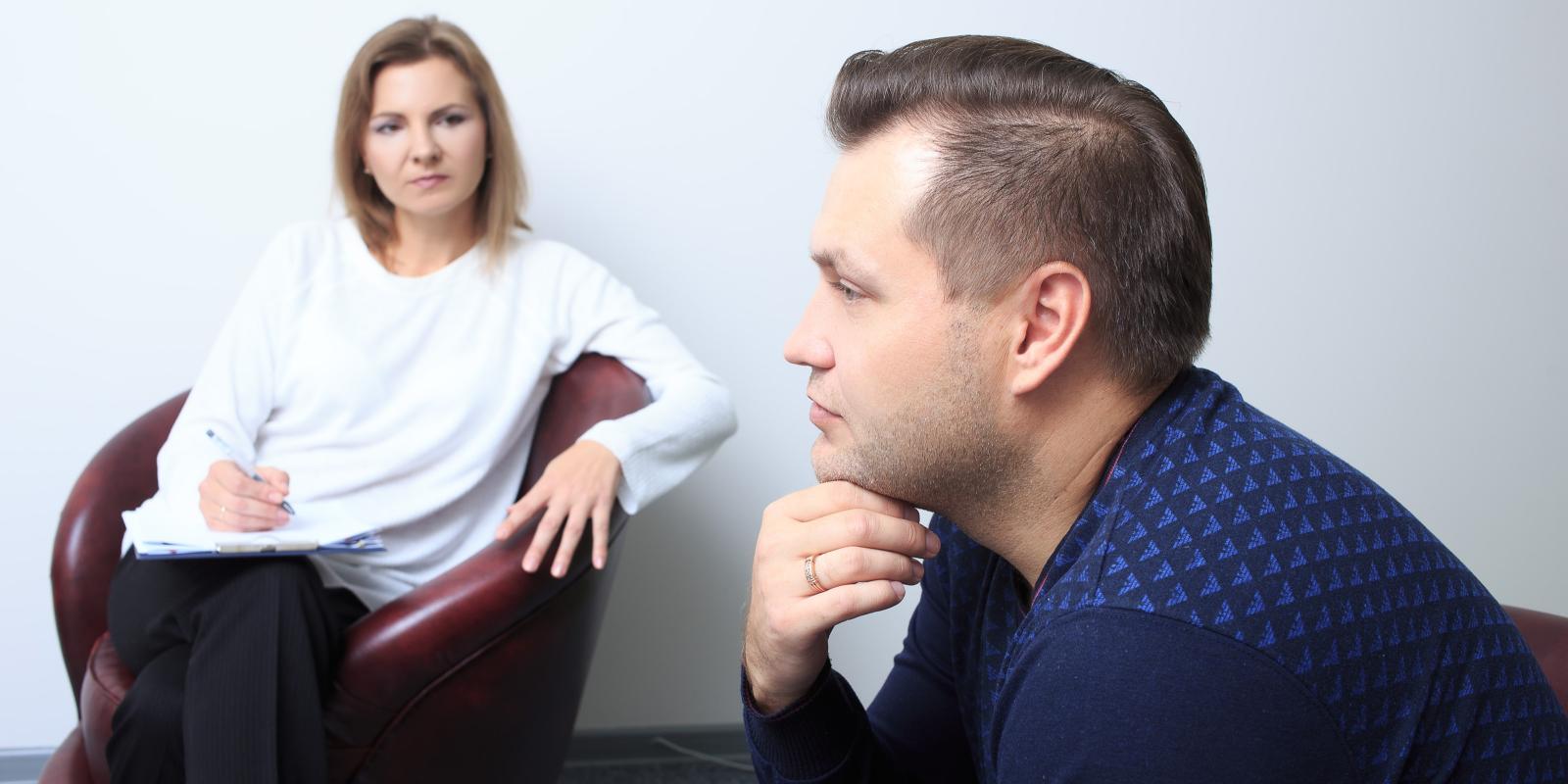 Bilde av kvinnelig terapeut som lytter til en mann. Begge er hvite.
