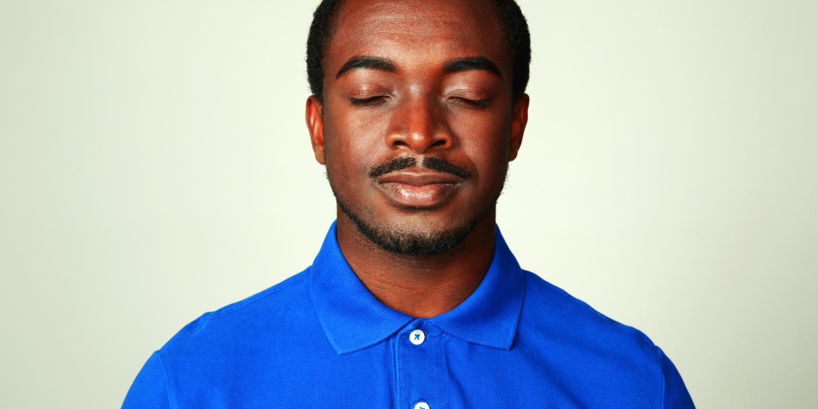 Bilde av melaninrik mann i blå skjorte med lukkede øynene.