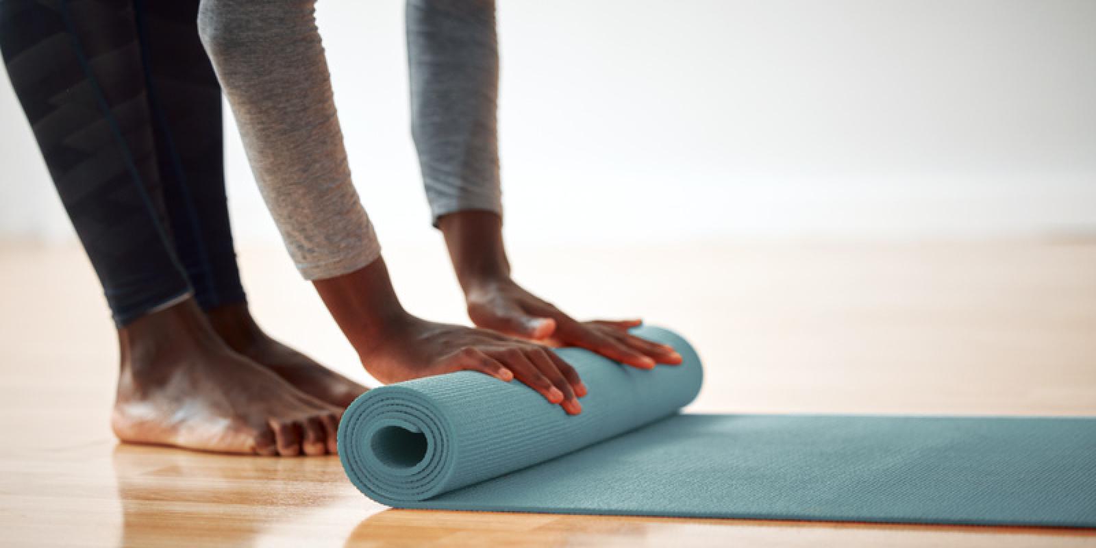 Hender som ruller ut en yogamatte
