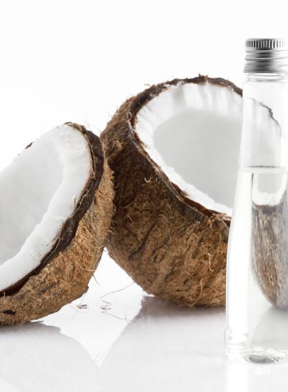 Delt kokosnøtt og to blankeflasker med kokosolje.