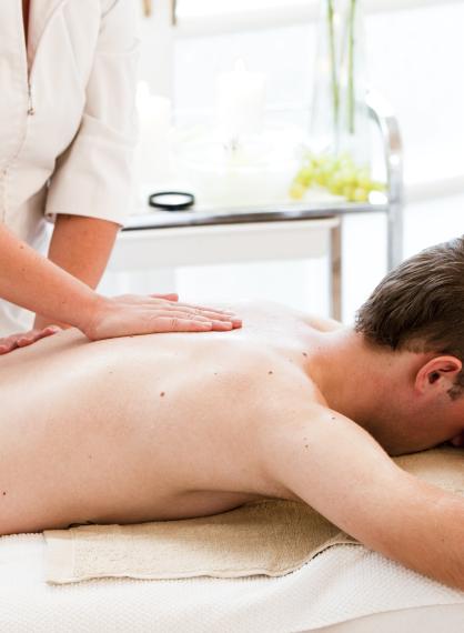 Bilde av hvit mann som ligger på behandlingsbenk og får massasje på ryggen