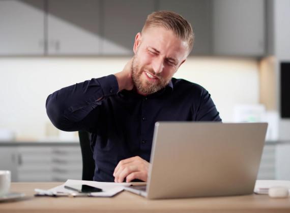 Mann bak laptop på skrivebord