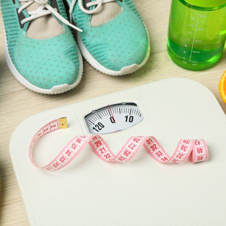 Bilde av vekt, målebånd, en halv appelsin, grønn drikkeflaske, turkise joggesjo, blått håndkle og bananer. Illustrasjonsfot: Mostphotos.com