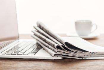 Foto av laptop og liten bunke med aviser og en kaffekopp